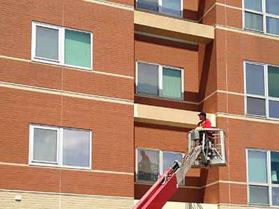 Window cleaner on lift cleans windows on retirement facility building