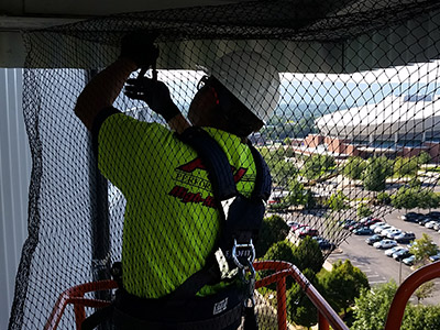 Worker installs bird control netting on high-rise building