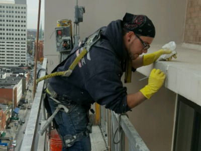 Worker in a city provides building maintenance services on high-rise building
