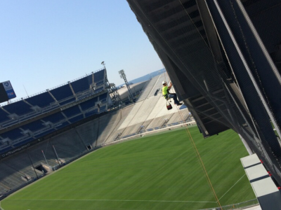 Worker suspended from rope cleans exterior of sports stadium